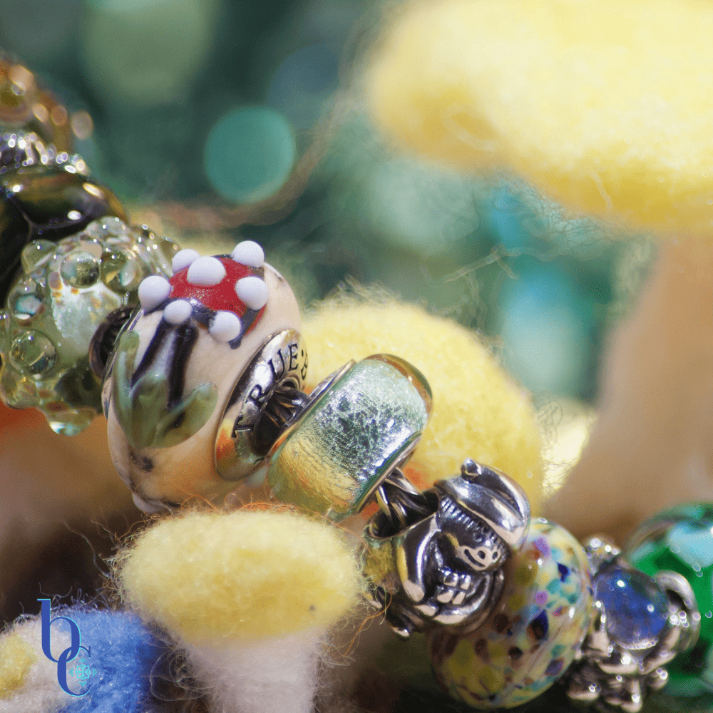 Atmospheric photo of a TrueBeadz Fly Agaric bead on a bracelet, with a dark olive background illuminated by soft, out-of-focus fairy lights mimicking fireflies.