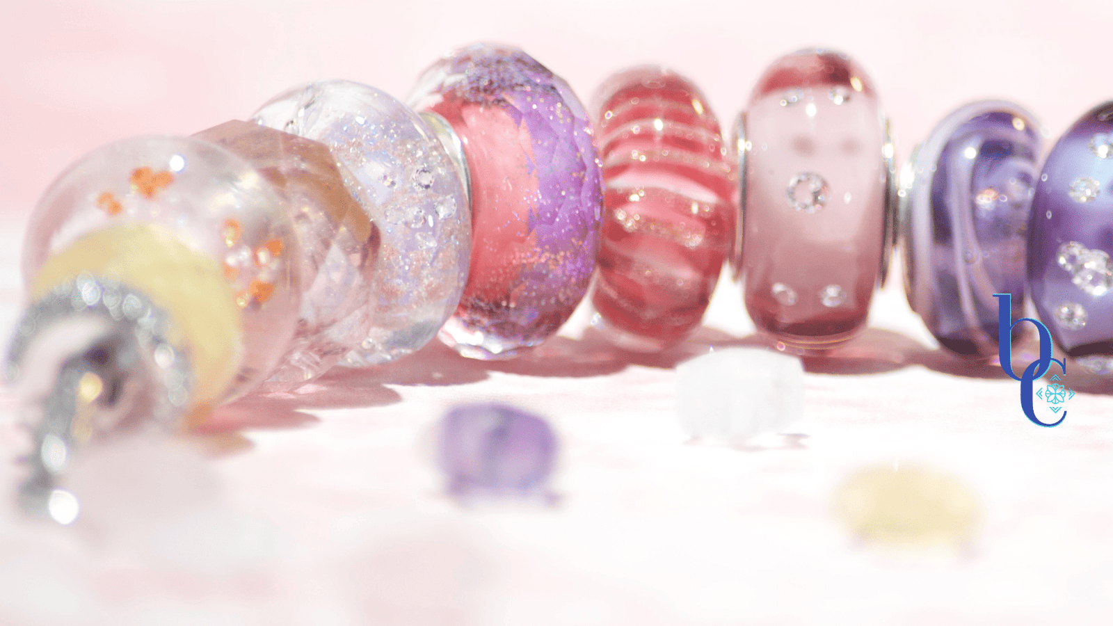 Image of an etheral ombre European bracelet design by BijouxChat.com that features am ombre of beautifully colored beads progressing from one that mimics the light of dawn to one that mimics the light of dusk. Each glass bead is different and represents the feeling of the "time of day". Set on a pale pink background with scattered gemstone stars around it.