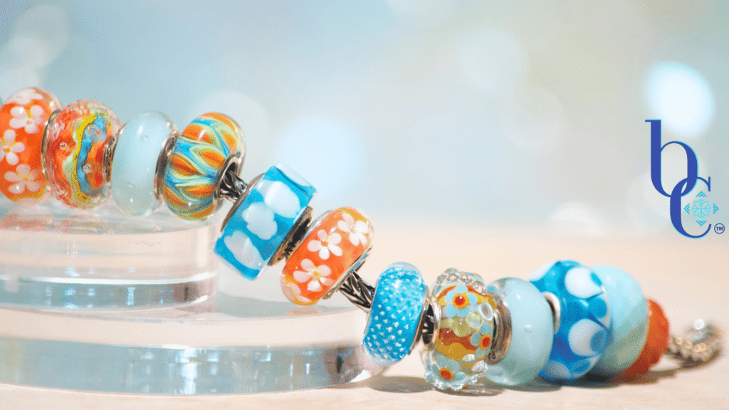 Banish the beige with our latest case study: Rhythm in Glass. Discover how to style a high-impact, complementary charm bracelet using bold cyan and tangerine artisan glass.