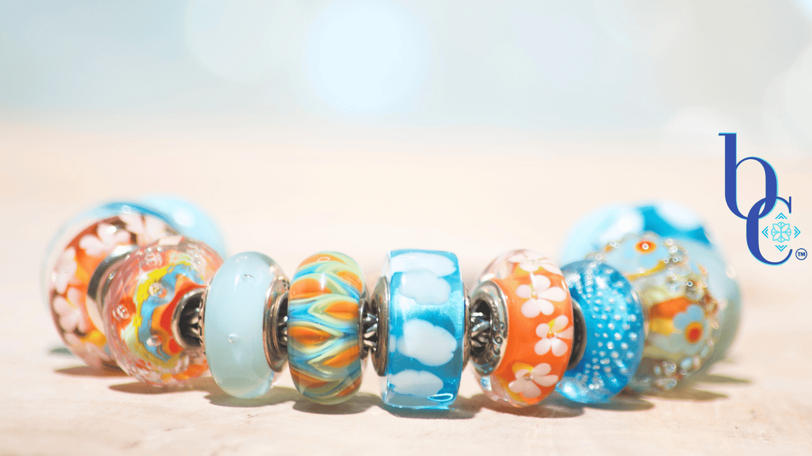 Banish the beige with our latest case study: Rhythm in Glass. Discover how to style a high-impact, complementary charm bracelet using bold cyan and tangerine artisan glass.