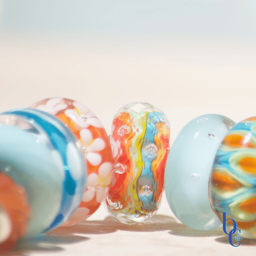 Banish the beige with our latest case study: Rhythm in Glass. Discover how to style a high-impact, complementary charm bracelet using bold cyan and tangerine artisan glass.