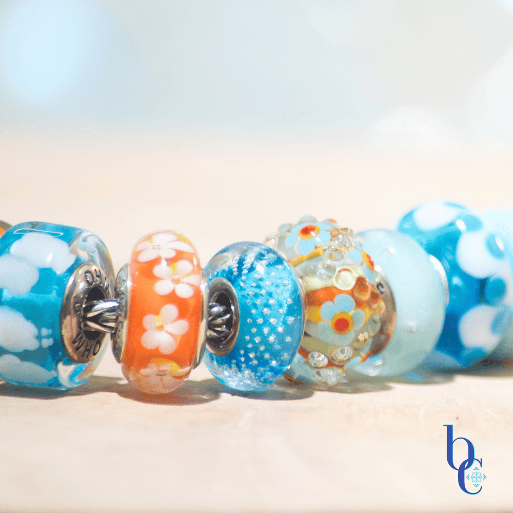 Banish the beige with our latest case study: Rhythm in Glass. Discover how to style a high-impact, complementary charm bracelet using bold cyan and tangerine artisan glass.
