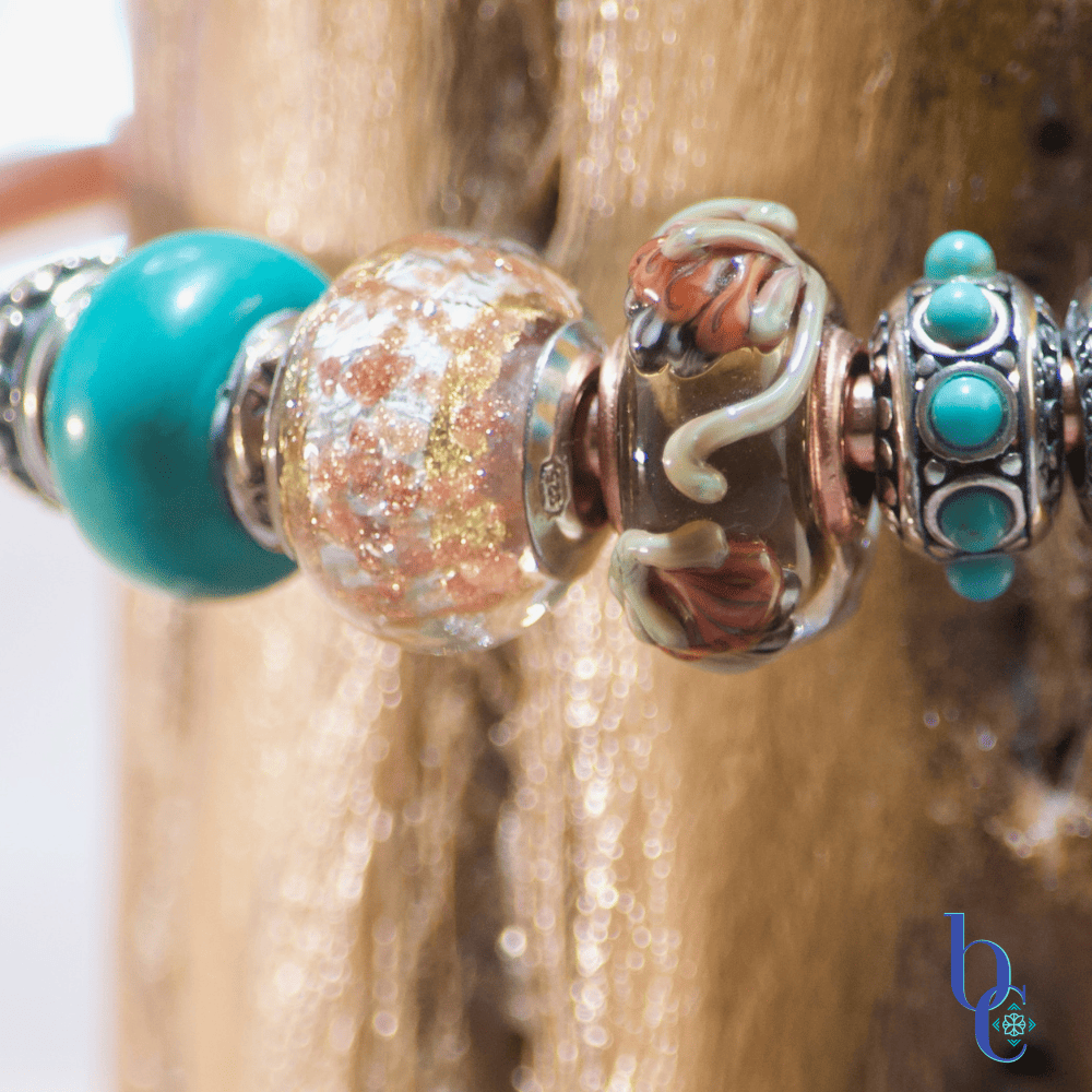 A macro image showing the featured beads of the Gilded Mesa design, a Kamane rooted bloom glass bead, a copper and gold glitter glass bead and a Redbalifrog turquoise bead.