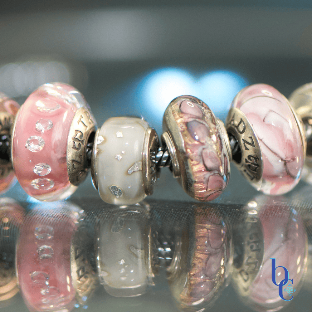 A high-contrast studio macro photograph capturing the rich textural transitions from industrial matte surfaces to shimmering glass facets, emphasizing the butterfly wing motif  and silver flakes of the charms.
