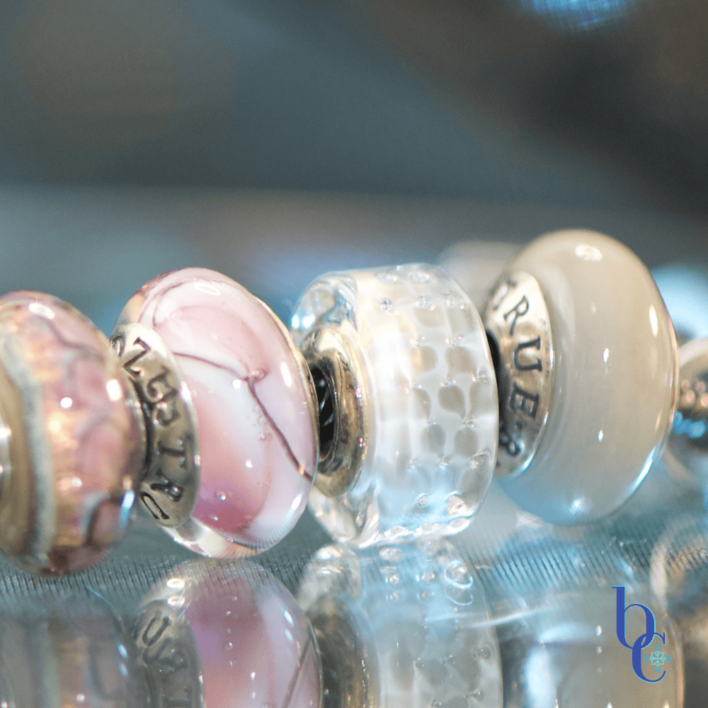 A high-contrast studio macro photograph capturing the rich textural transitions from industrial matte surfaces to shimmering glass facets, emphasizing the textures and details of the charms.
