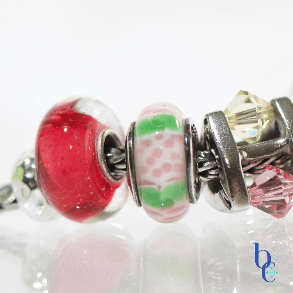 Extreme close-up of  artisan glass beads showing their details and color flanked by various beads in the design.