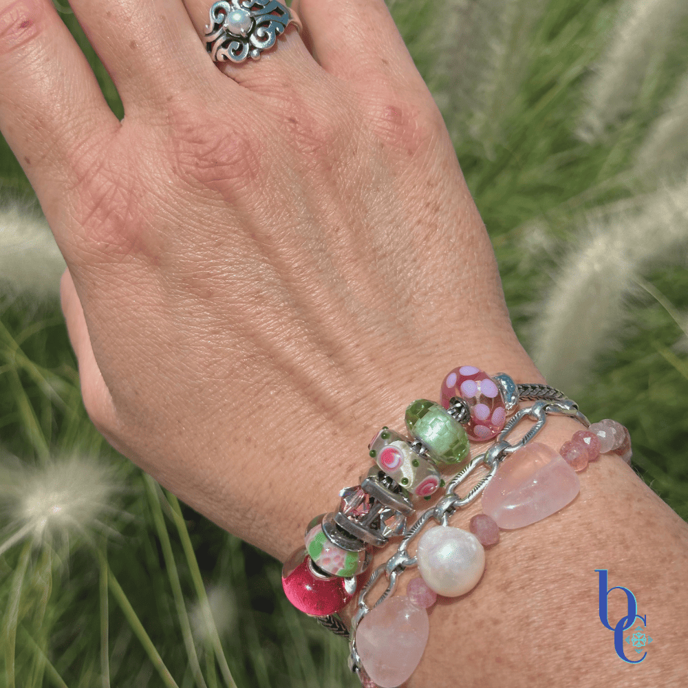 Close-up of  artisan glass beads showing their details and color flanked by various beads in the design with a companion bracelet stack in outdoor light on a woman's wrist.