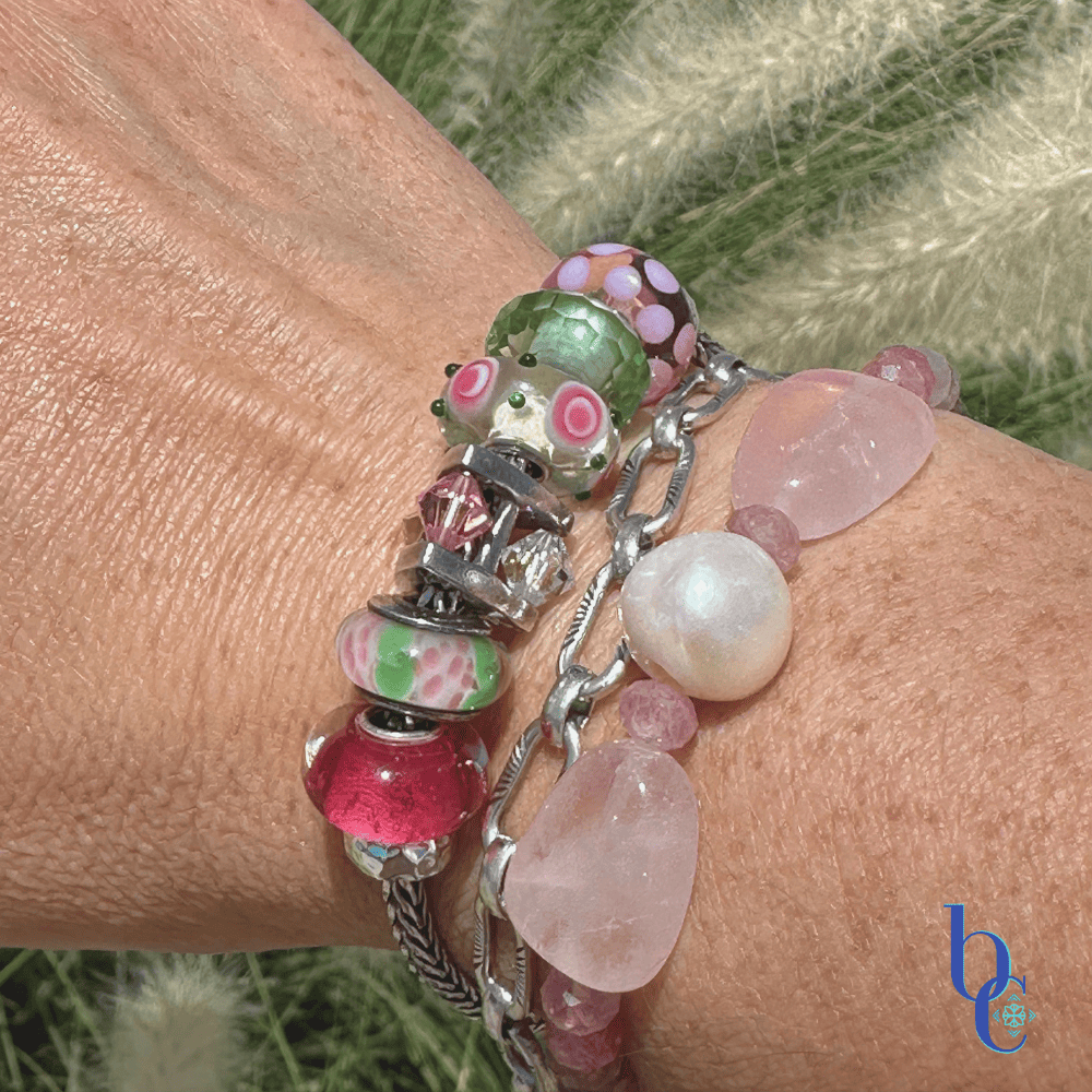 Close-up of  artisan glass beads showing their details and color flanked by various beads in the design with a companion bracelet stack in outdoor light on a woman's wrist.