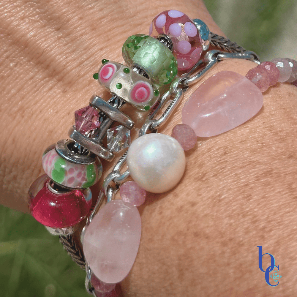 Close-up of  artisan glass beads showing their details and color flanked by various beads in the design with a companion bracelet stack in outdoor light on a woman's wrist.