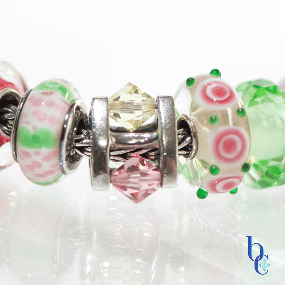 Extreme close-up of  artisan glass beads showing their details and color flanked by various beads in the design.