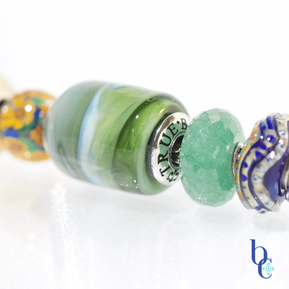 Explore "Ripples in Glass"—a 5-piece charm bracelet design inspired by Vermont summer lakeside life. Featuring TrueBeadz, Trollbeads, and natural faceted minerals styled for an artsy aesthetic on a white background.
