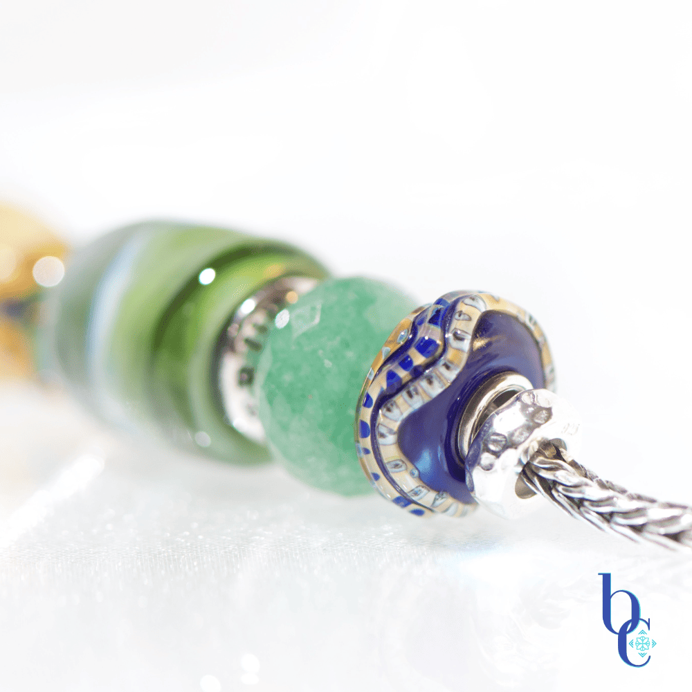 Explore "Ripples in Glass"—a 5-piece charm bracelet design inspired by Vermont summer lakeside life. Featuring TrueBeadz, Trollbeads, and natural faceted minerals styled for an artsy aesthetic on a white background.