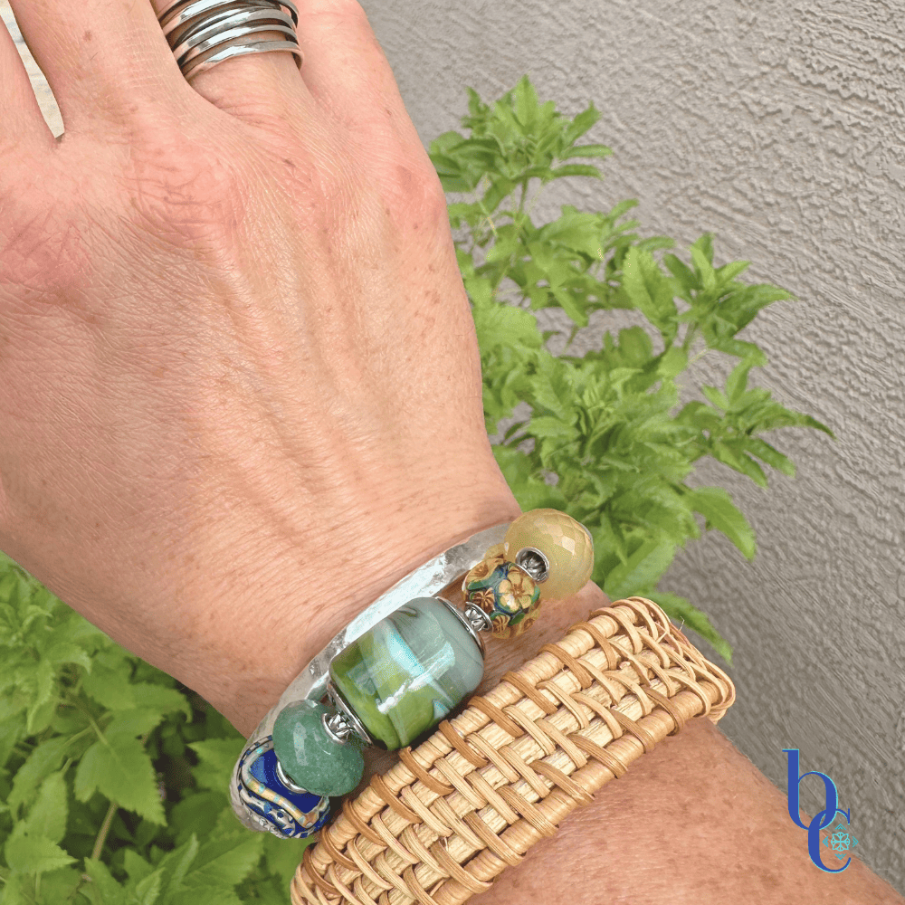 Explore "Ripples in Glass"—a 5-piece charm bracelet design inspired by Vermont summer lakeside life. Featuring TrueBeadz, Trollbeads, and natural faceted minerals styled for an artsy aesthetic on a woman's wrist.